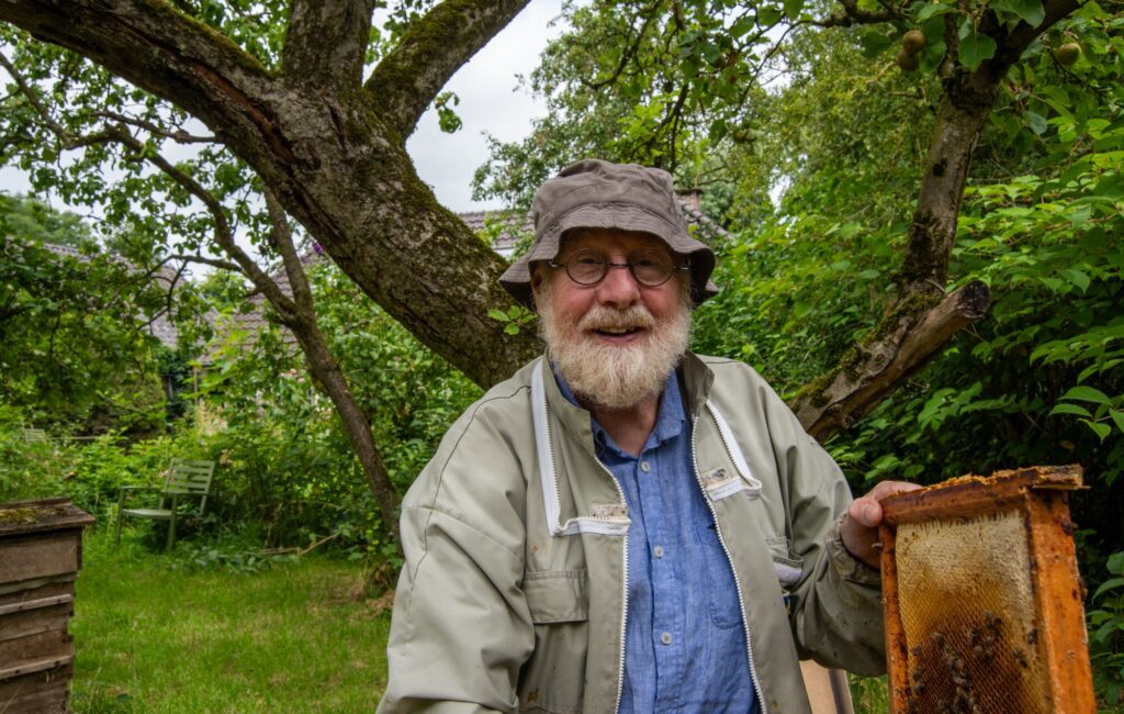 Bijenhouder Albert Muller met een honingraat in zijn tuin aan de Zeedijk in Nijbroek